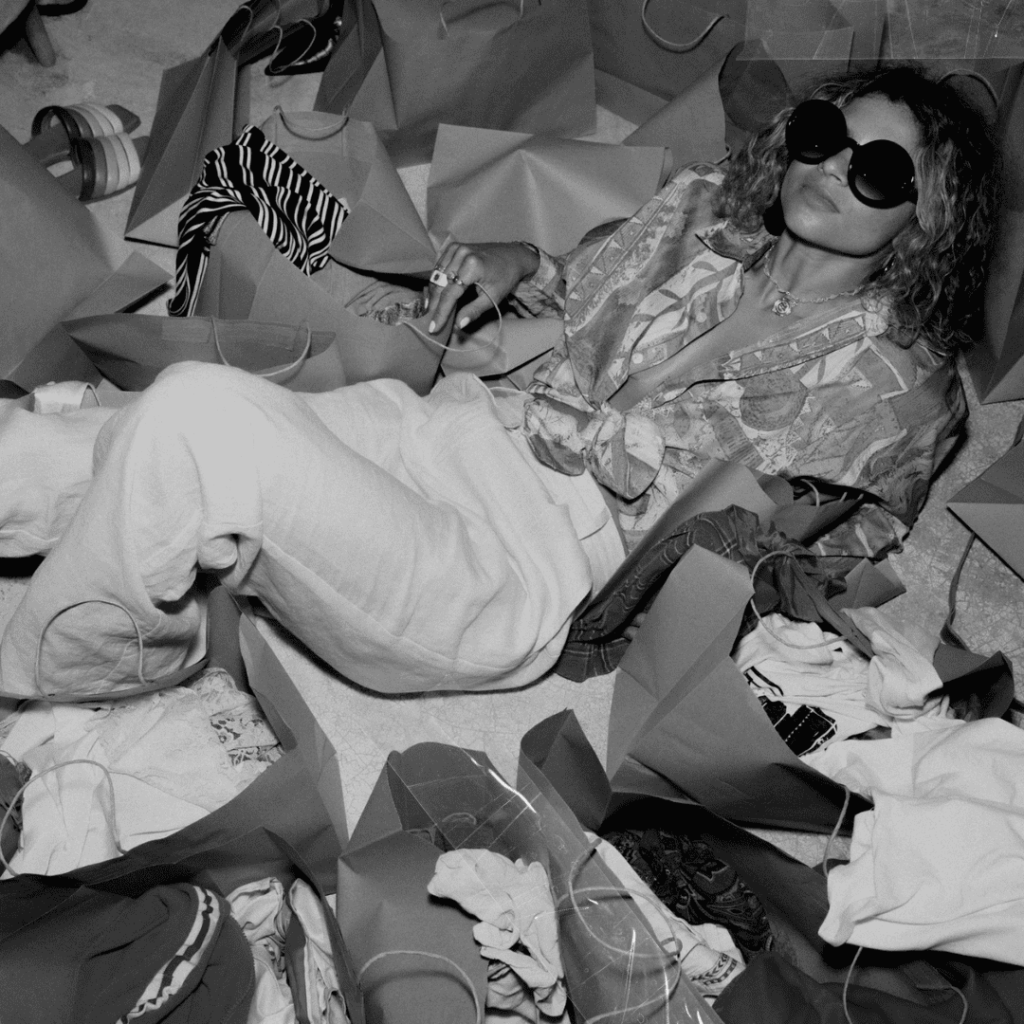Woman sitting in a pile of clothes contemplating life.