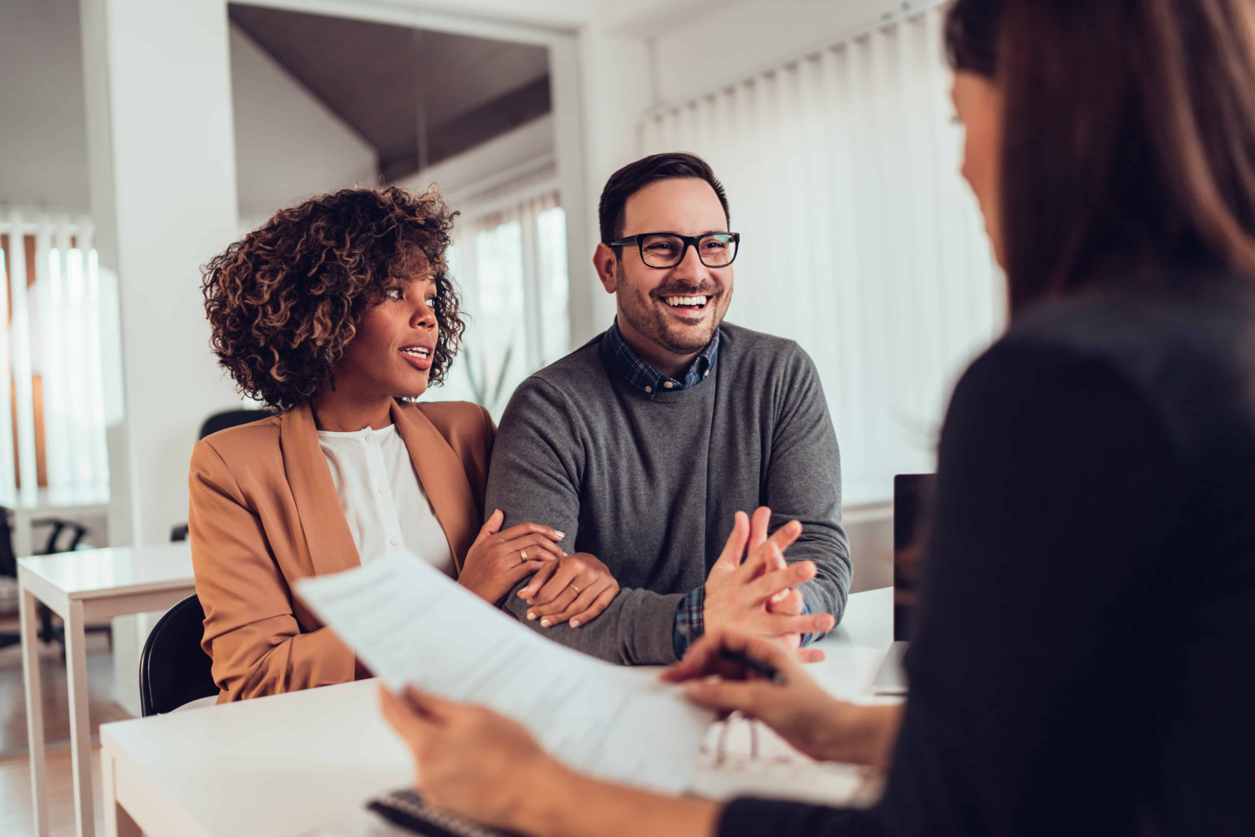 A couple at a bank getting a loan, the man is smiling while the woman is looking at him very nervously.