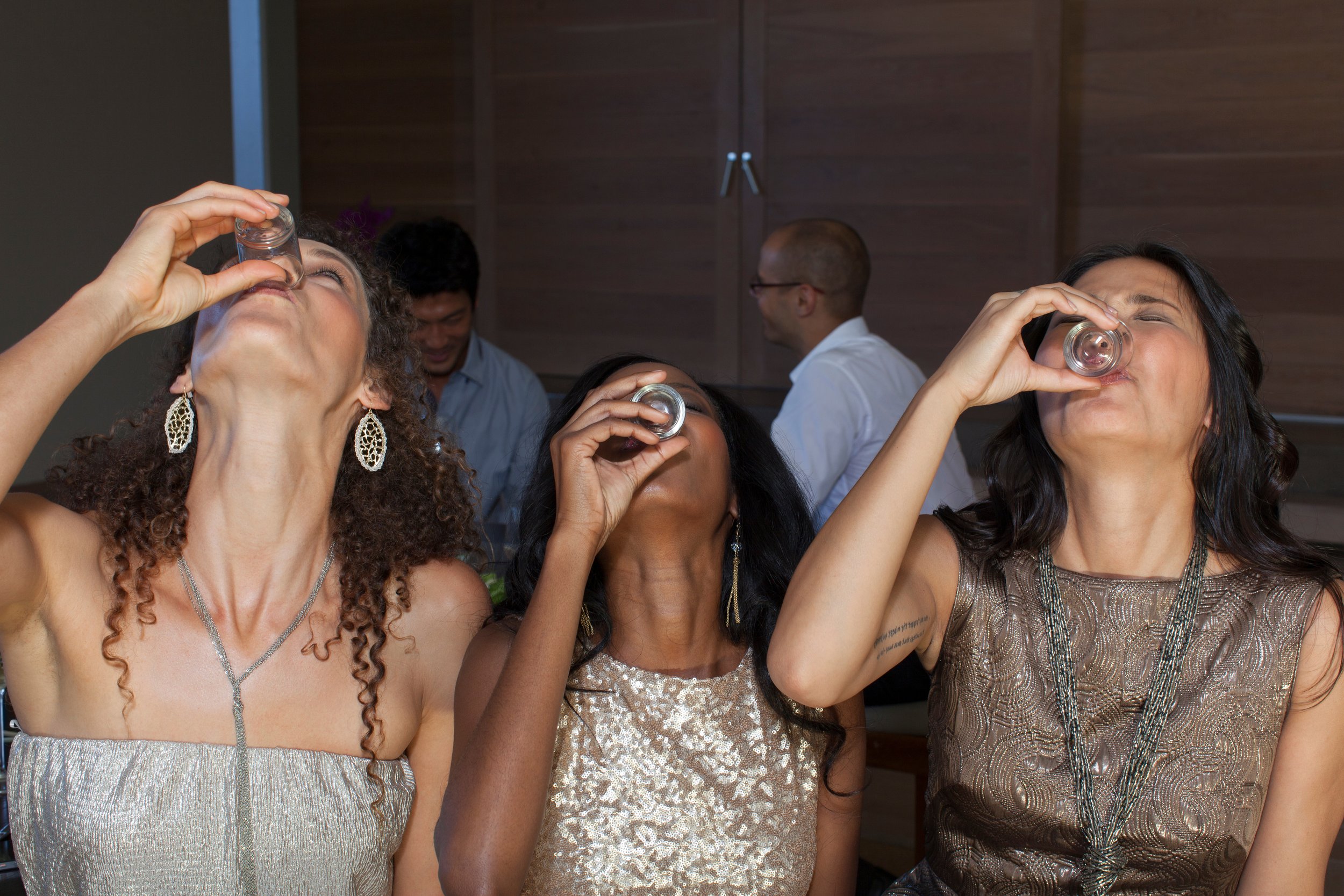 Three women taking shots of whiskey.