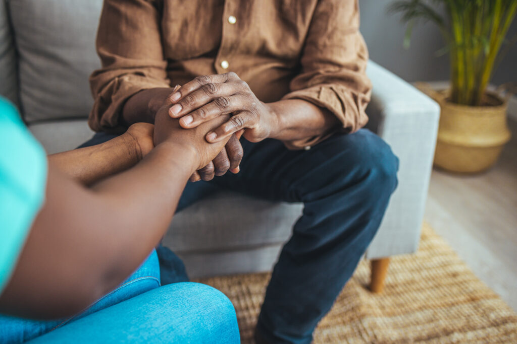 A young black couple sitting with a mental health professional holding hands wanting a faith based approach to their marriage problems.