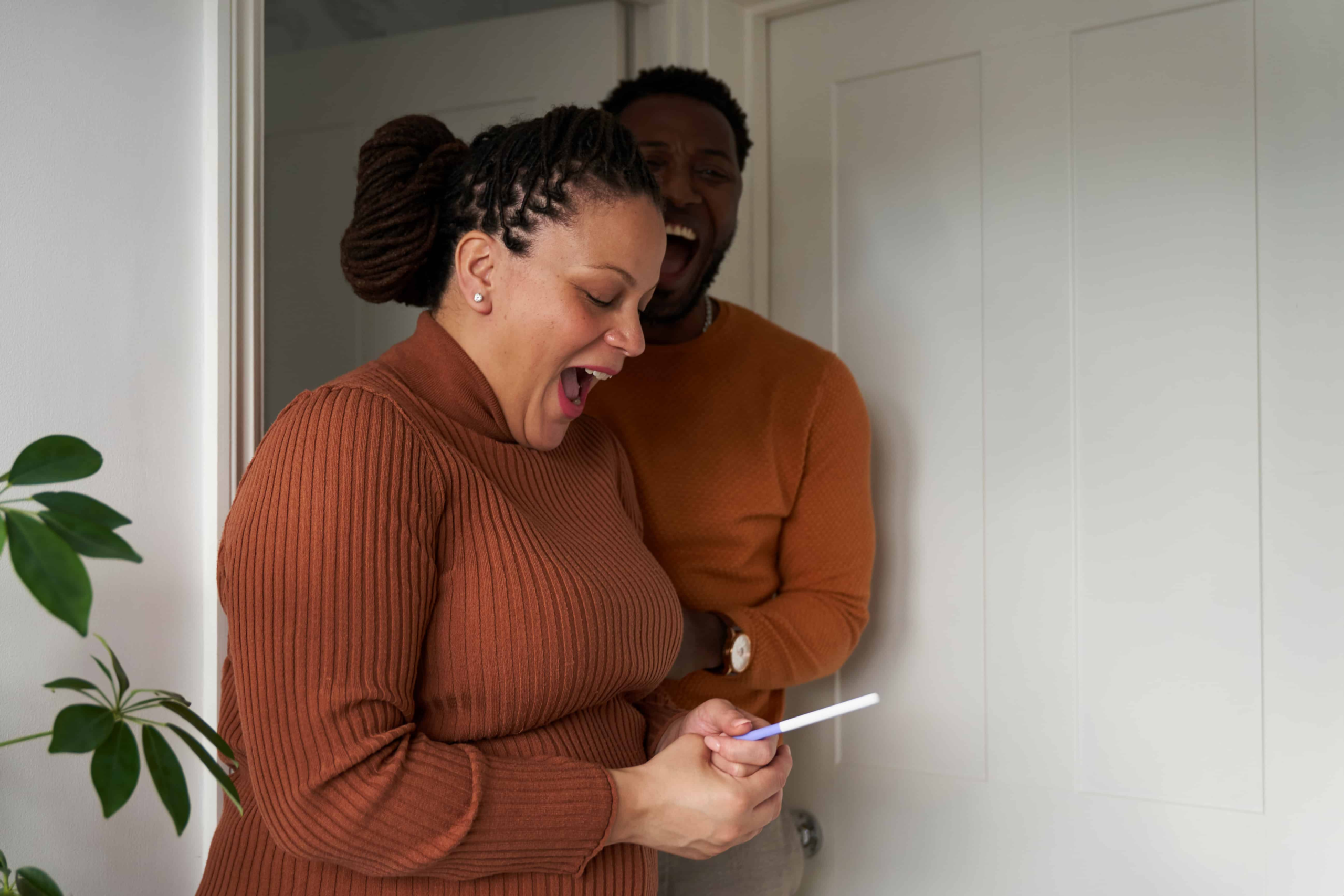 a couple wearing matching clothing. They just found out that they are pregnant, the men is very excited while the woman looks a little shocked and surprised.