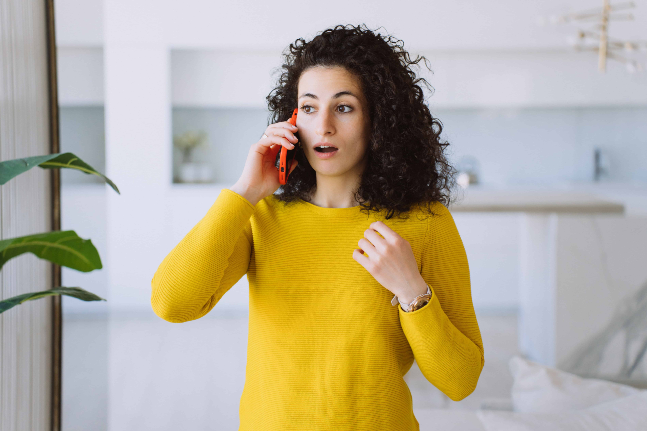 A woman with curly hair visible shaken by the news she received on the phone. Once again her partner is breaking promises he made about prioritizing their date nights.