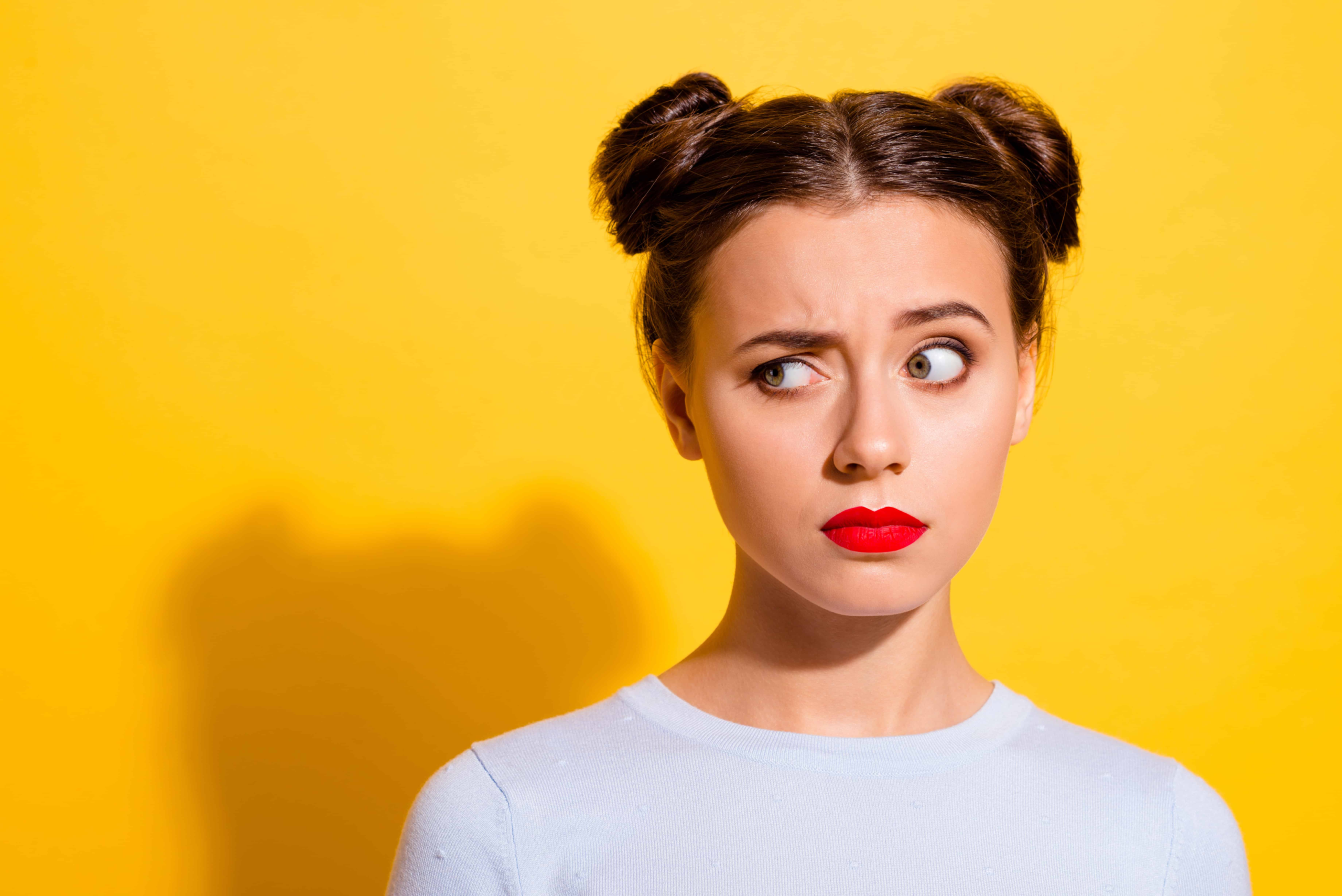 A woman with pig tails that is making a smug face. A friend said something to her that she did not like.