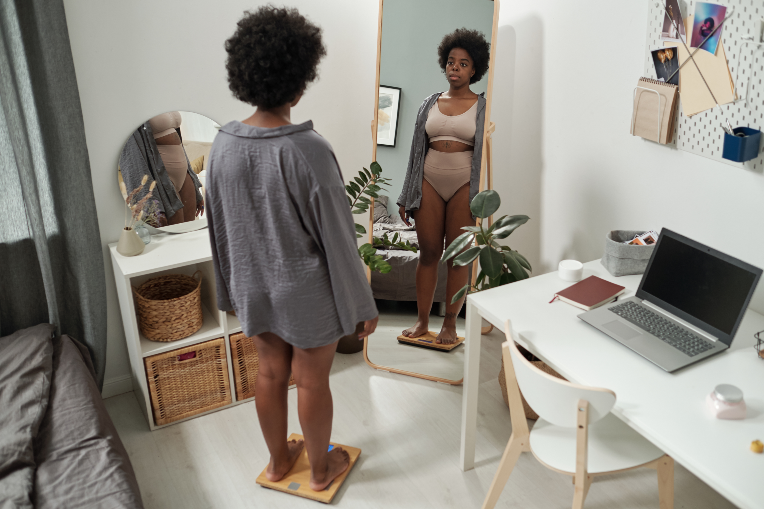 Woman in her bra and panties looking in the mirror, while on the scale not happy about her life. She is trying to figure out how to address her inner critic.