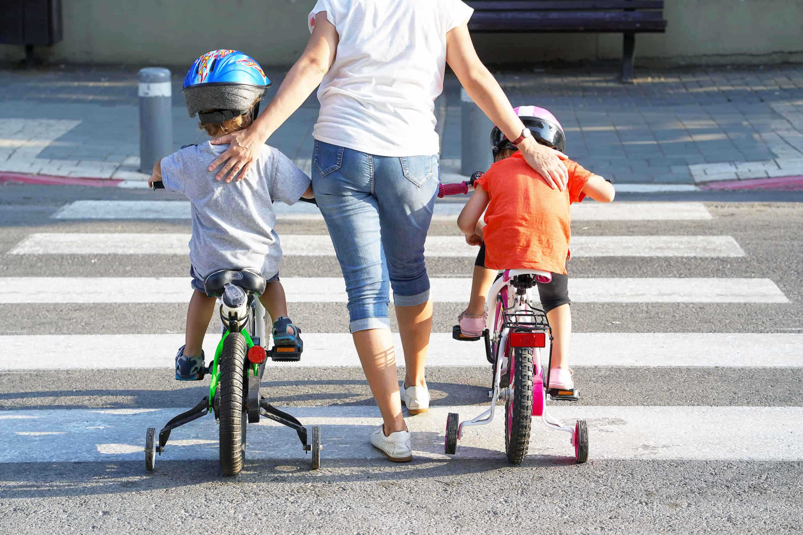 A family out and about riding their bicycles with training wheels and helmets.