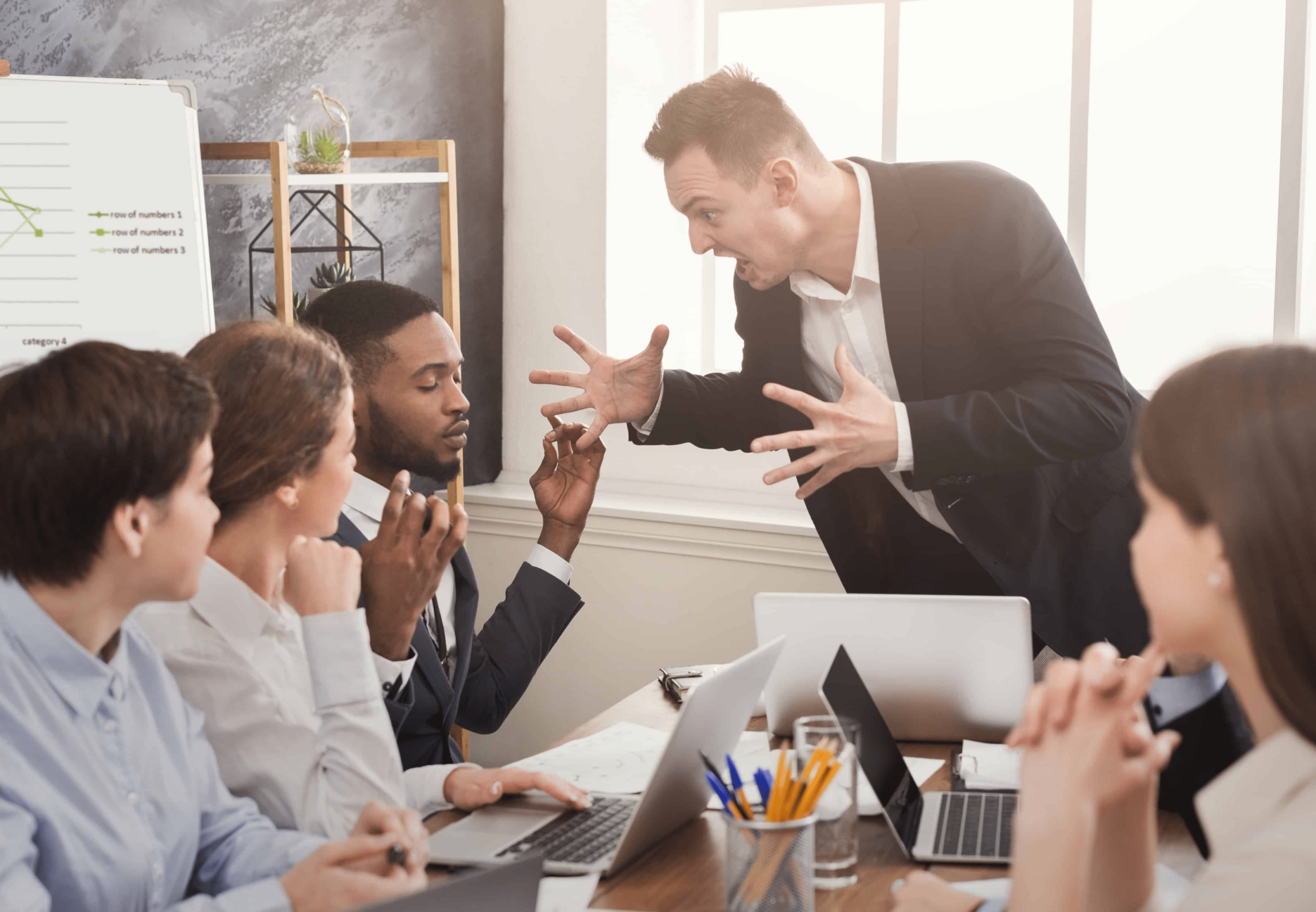 a man in a conference room yelling at his employees.