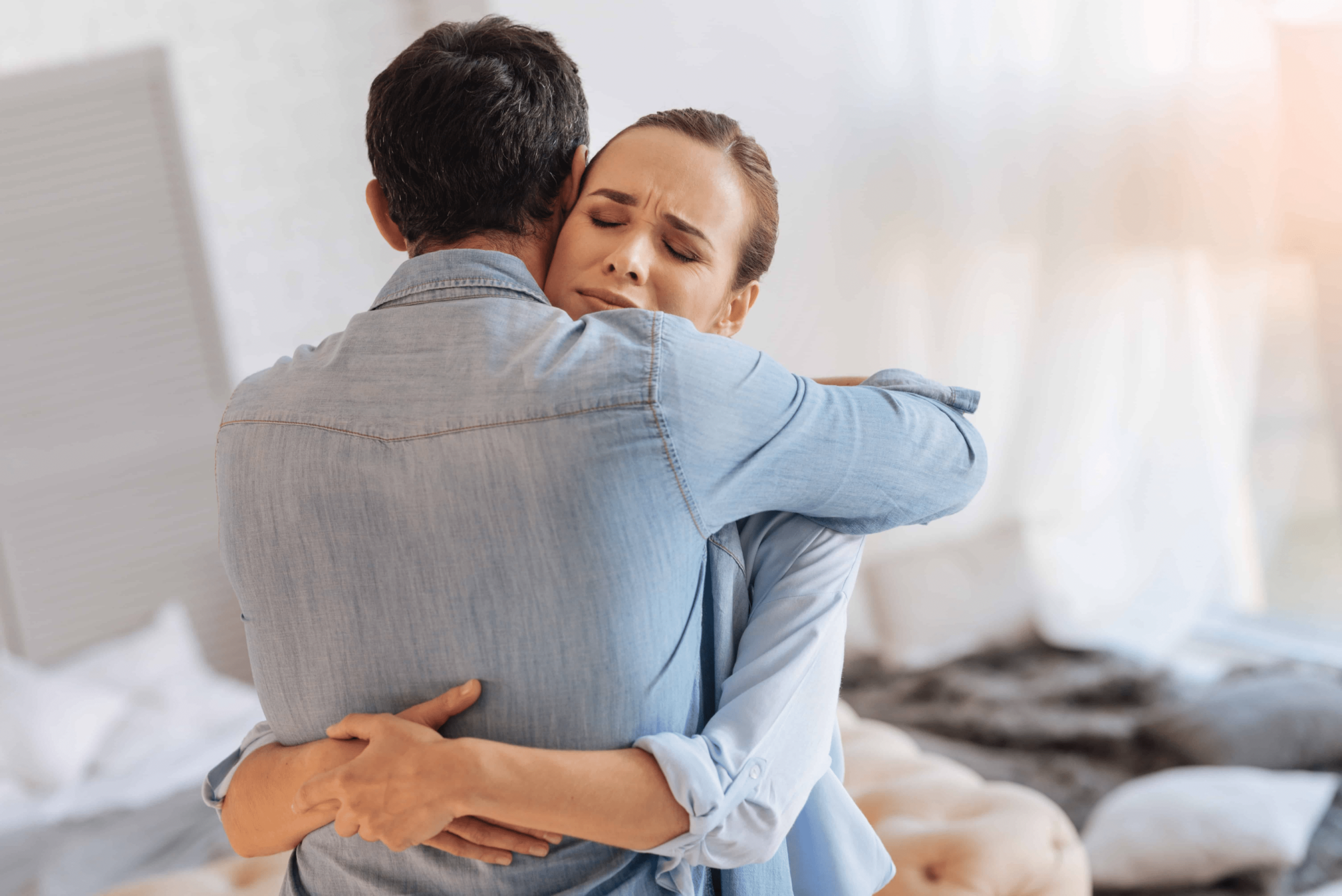 A couple hugging. The woman looks very emotional and very happy to have a hug from her husband.