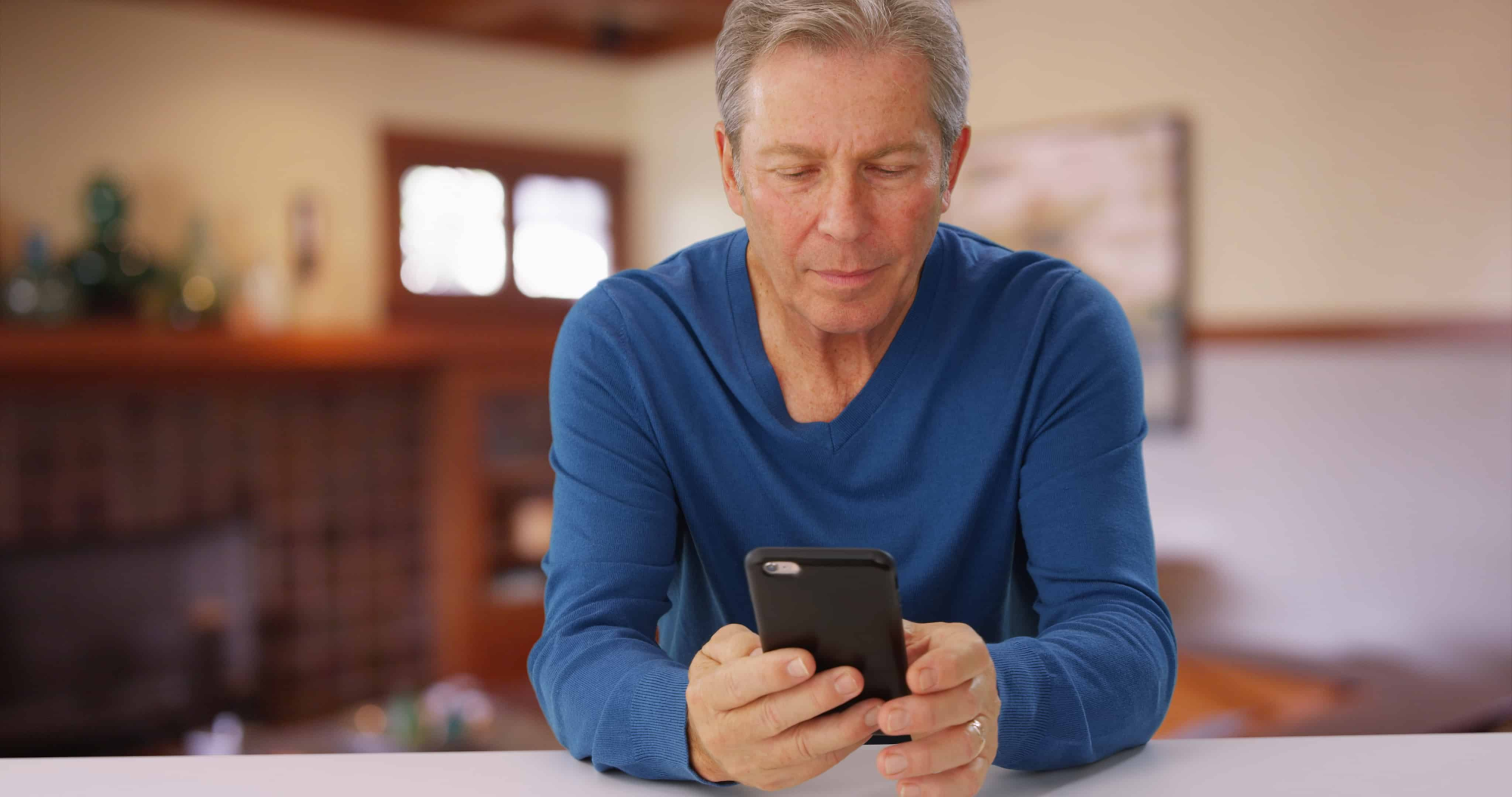 A man in a romantic relationship staring at his phone while waiting for his wife to text him.