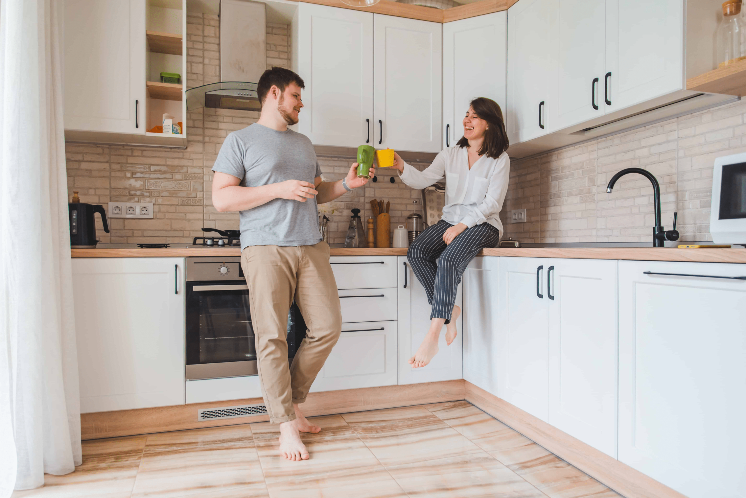 A couple in the kitchen drinking coffees together and talking about their life.