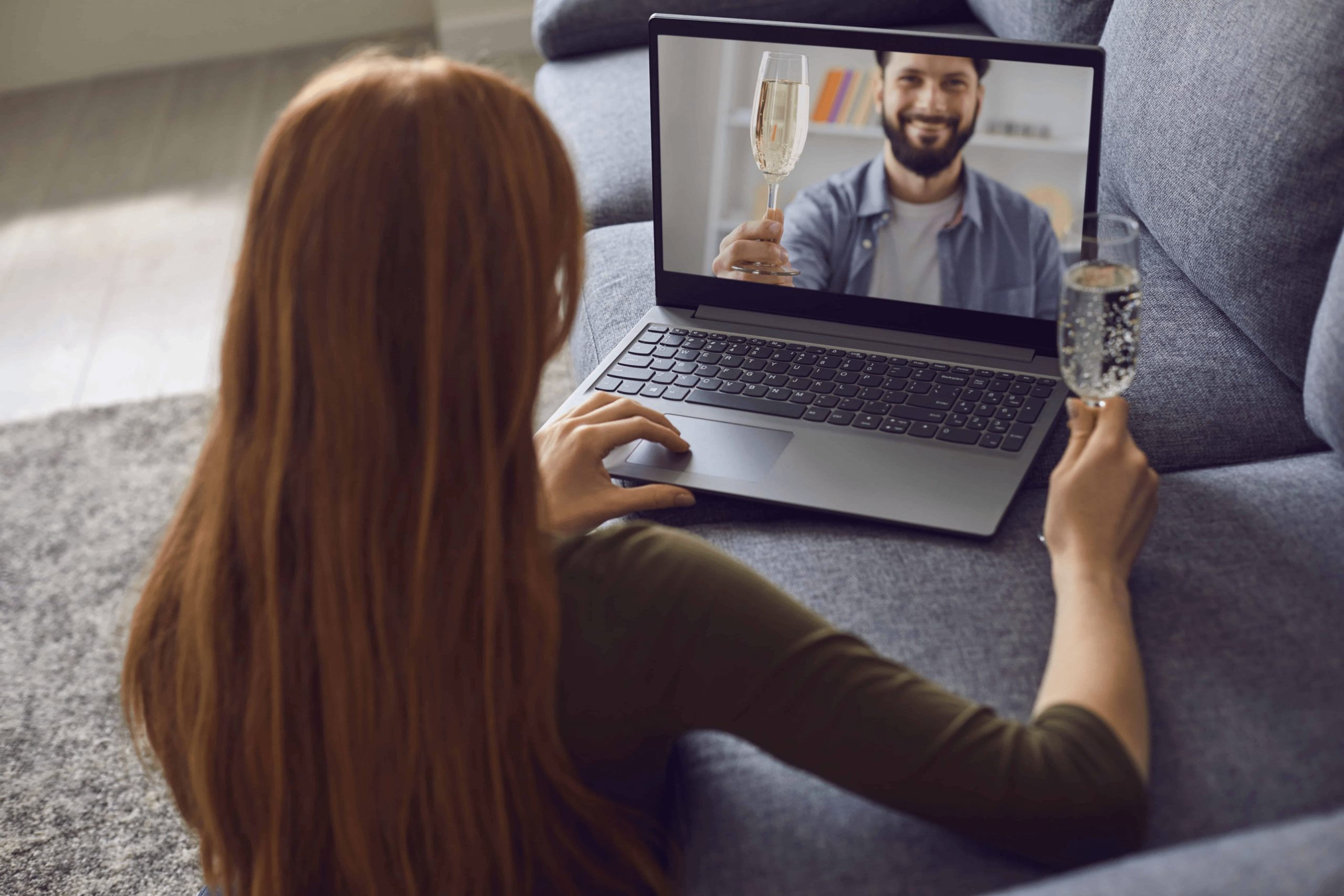 A couple that is doing online dating, they are both drinking champagne as they stare at their computers.