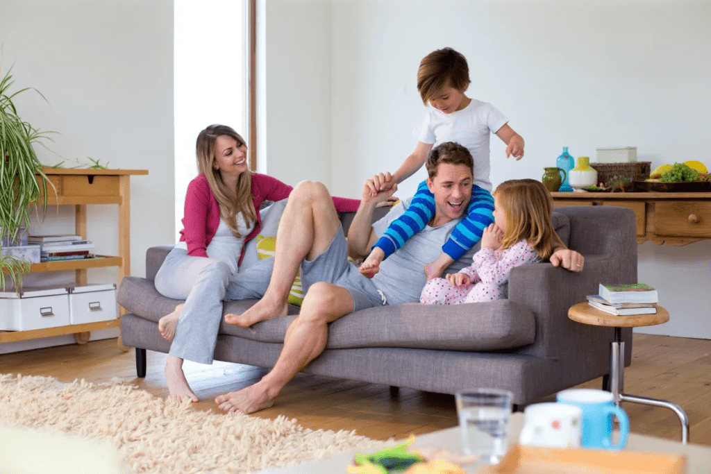 a family hanging out and playing, the son is on the dads shoulders as everyone is laughing and having a great time.