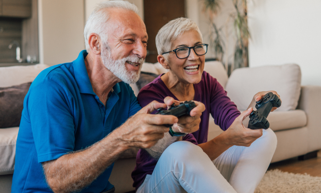 an older couple sitting together on the couch playing video games together.