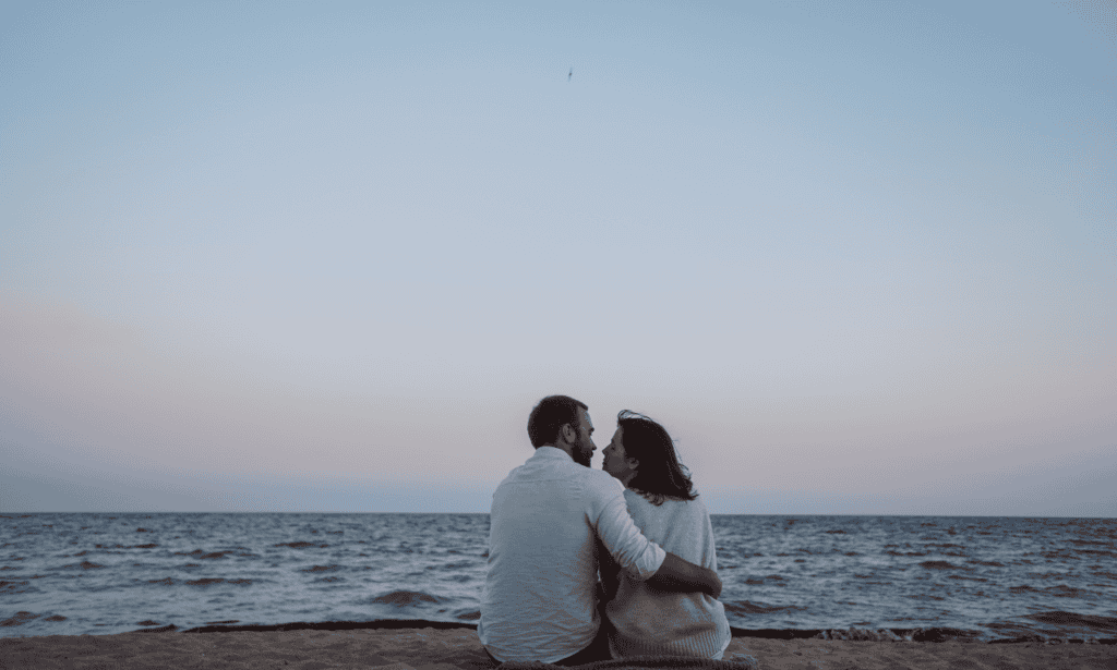 a couple at the beach relaxing as they prepare for their first kiss.