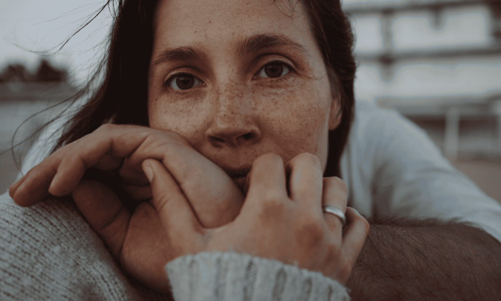 Closeup of a woman with a man hugging her from behind.