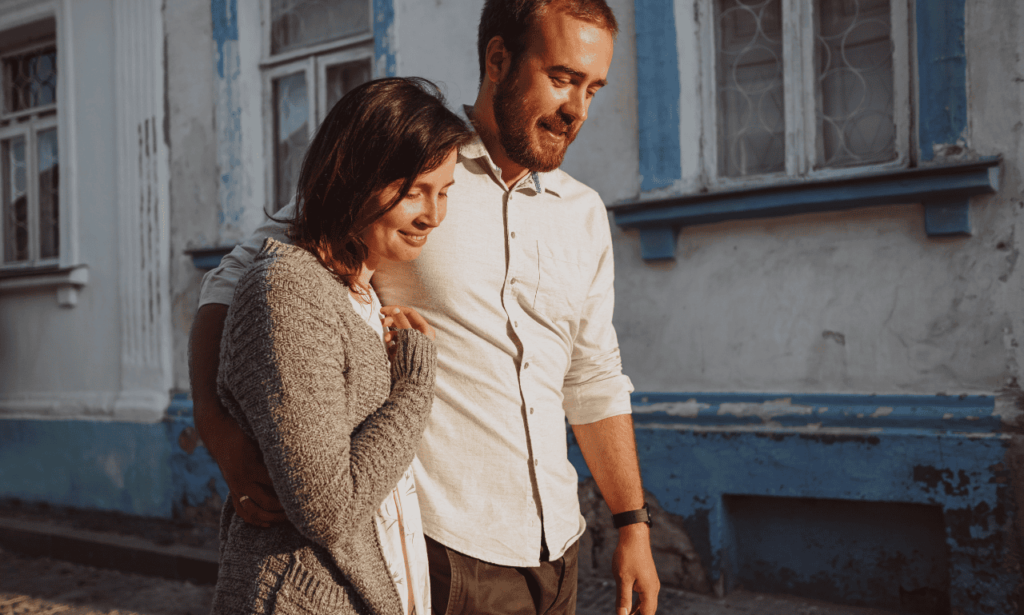 white couple walking in the street holding each other talking.