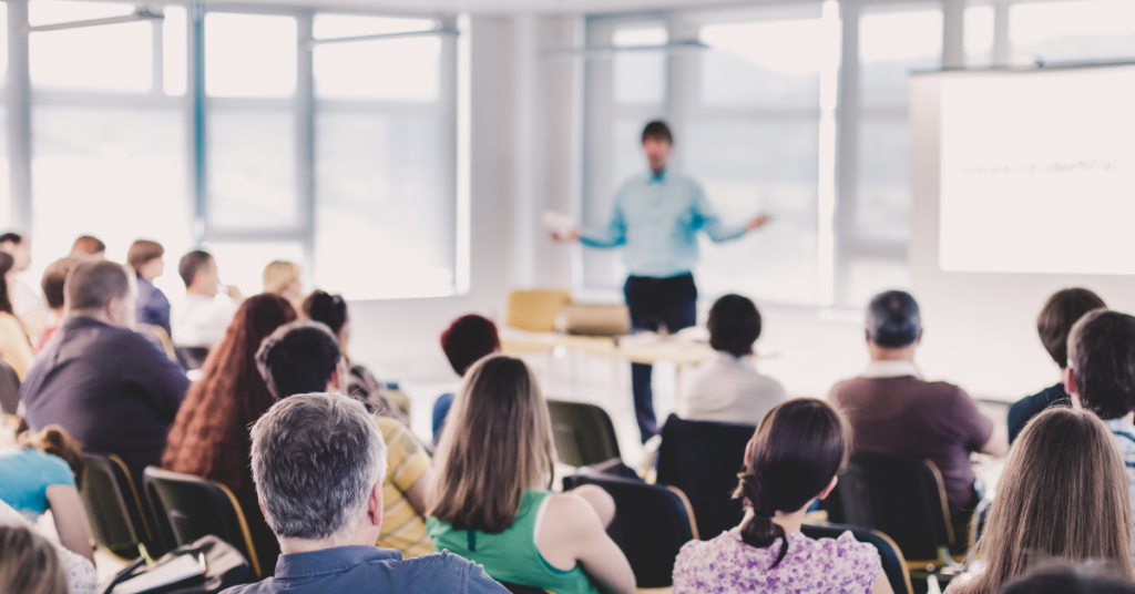 A guy in front of a room giving a speech