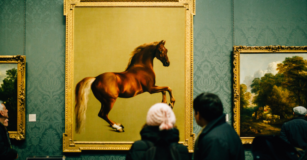 people at an art gallery looking at a framed picture of a horse!