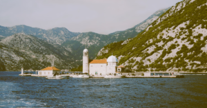 picture of an island with a boat watchtower and mountains