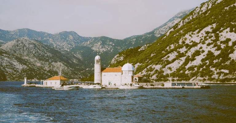 picture of an island with a boat watchtower and mountains