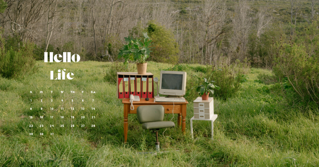 Picture of a computer on the desk in a field. With the words hello life and a calendar.