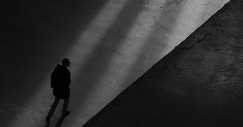 A man standing in a doorway walking into a dark building.