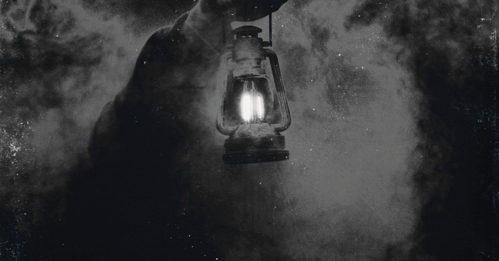 A person walking inn pitch blackness holdinng a light up attempting to see what's in front of them.